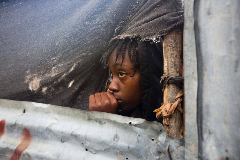 En ung flicka tittar på medan hennes hus evakueras i Tabarre, Haiti.