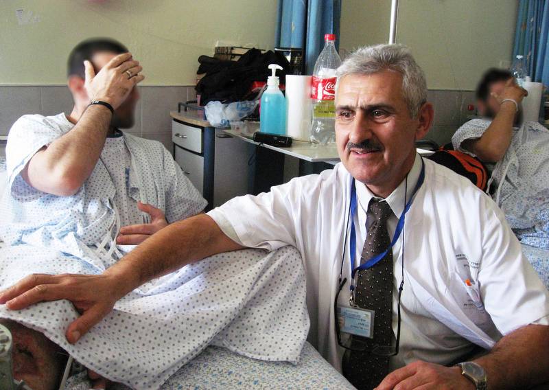 Professor Alexander Lerner med de syriska patienterna Fares och Abu Hamzeh, som täcker sina ansikten, på det israeliska Ziv-sjukhuset i Safed.