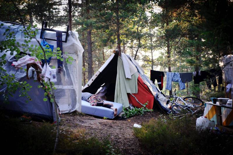 En romsk tiggare sover på en madrass utanför ett egenbygt tält i ett läger i Högdalen, Stockholm.