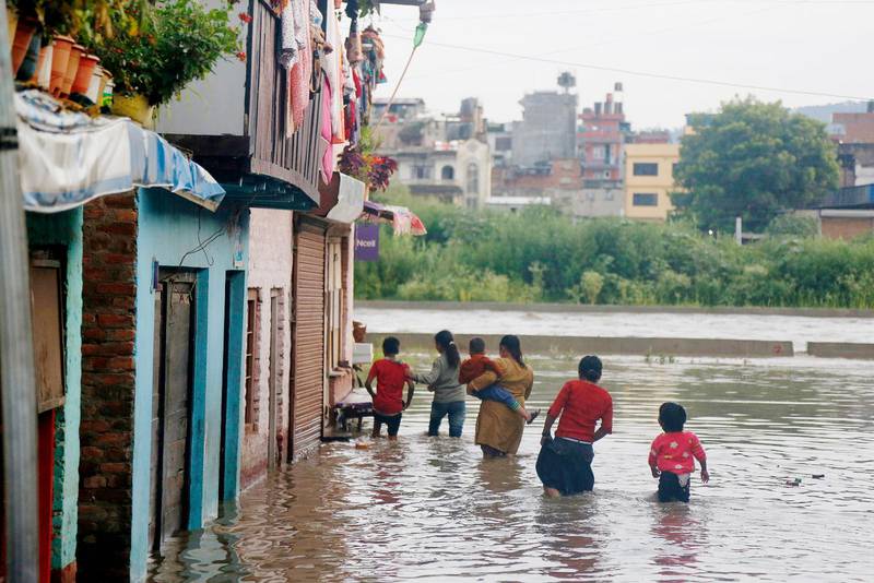 Invånare i huvudstaden Kathmandu försöker ta sig fram till sina översvämmade hus.