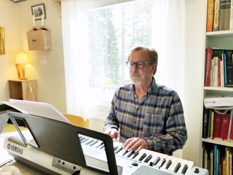 Per Harling, präst och psalmförfattare, spelar på sitt piano i stugan i Hälsingland.