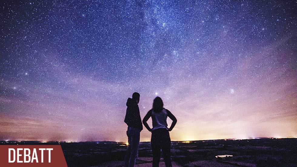 Två personer tittar upp mot stjärnhimlen.