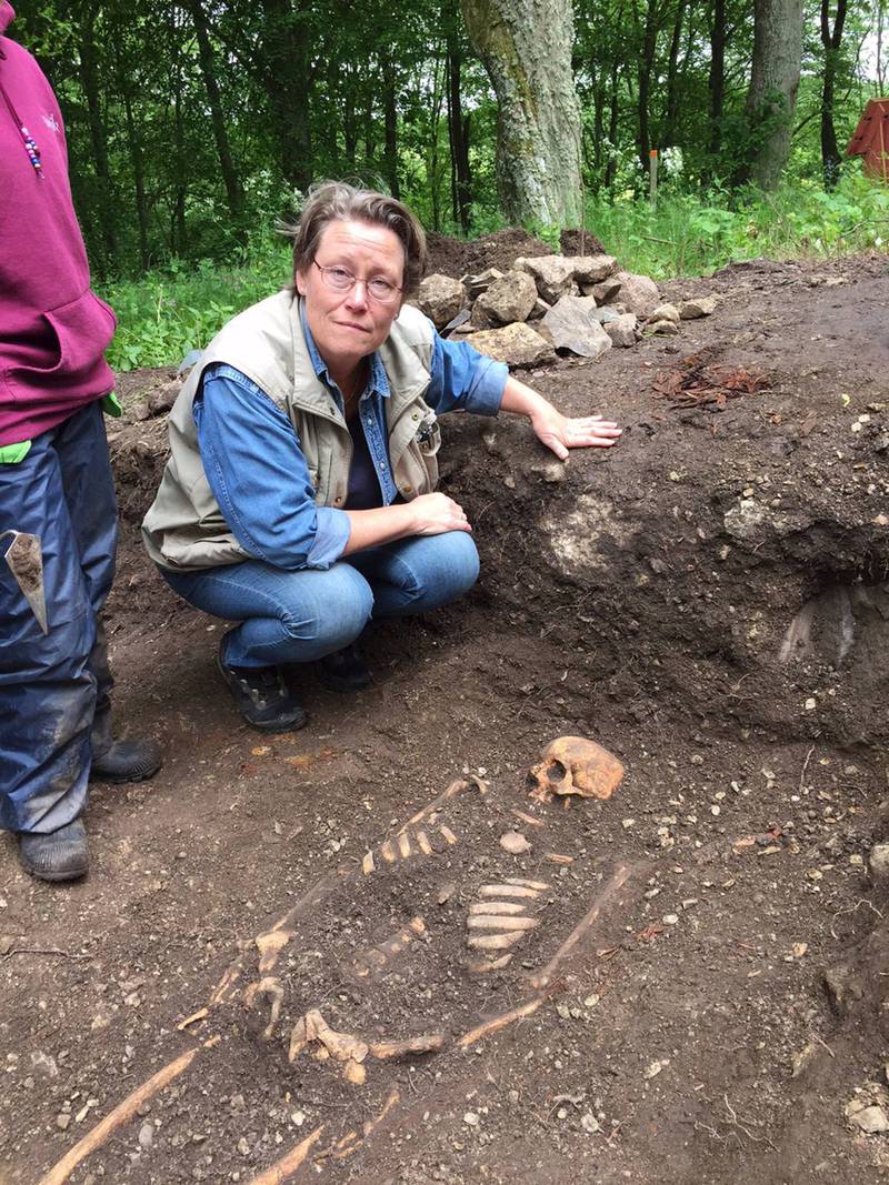Arkeologen Marie Vretemark intill ett framgrävt mansskelett.