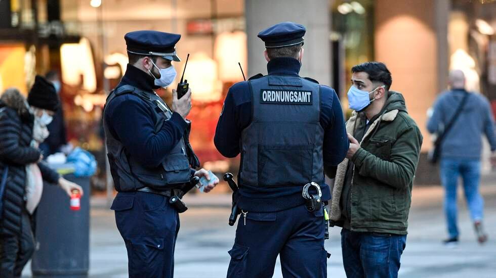 Ordningsvakter kontrollerar att förbipasserande bär munskydd. Bilden är från Dortmund i västra Tyskland.