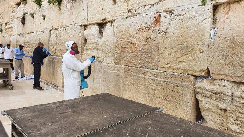 Västra muren i Jerusalem sanerades på tisdagen mot coronaviruset samtidigt som tiotusentals bönelappar plockas bort ur murens springor.