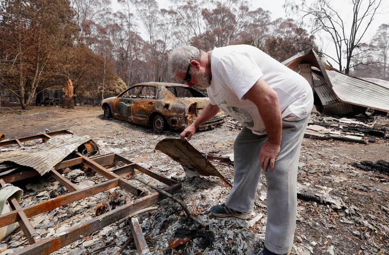 Lyle Stewart looks through burned debris at his destroyed house at Nerrigundah, Australia, Monday, Jan. 13, 2020, after a wildfire ripped through the town on New Year's Eve. The tiny village of Nerrigundah in New South Wales has been among the hardest hit by Australia's devastating wildfires, with about two thirds of the homes destroyed and a 71-year-old man killed. (AP Photo/Rick Rycroft)  XRR108