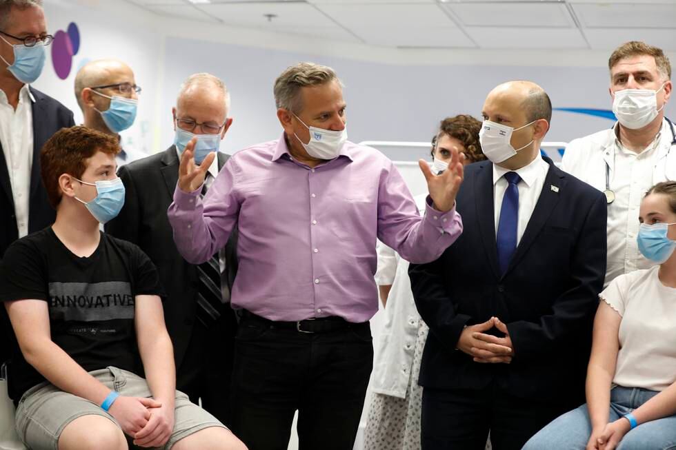 Israels premiärminister Naftali Bennett, till höger i mörk kostym, lyssnar på hälsominister Nitzan Horowitz i lila skjorta under ett besök på ett sjukhus i juni.