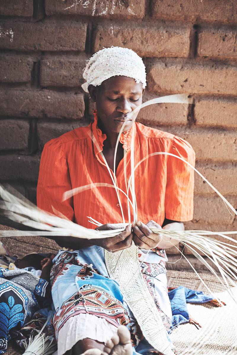 MOR. Fembarnsmamman Khrissy från Malawi sitter och väver mattor. Från och till har familjen mat.