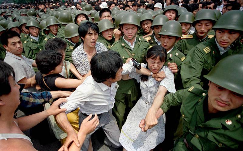En ung kvinna hamnar i kläm mellan demonstranter och soldater när dessa försökte skingra folksamlingen utanför Folkets hus i Peking.