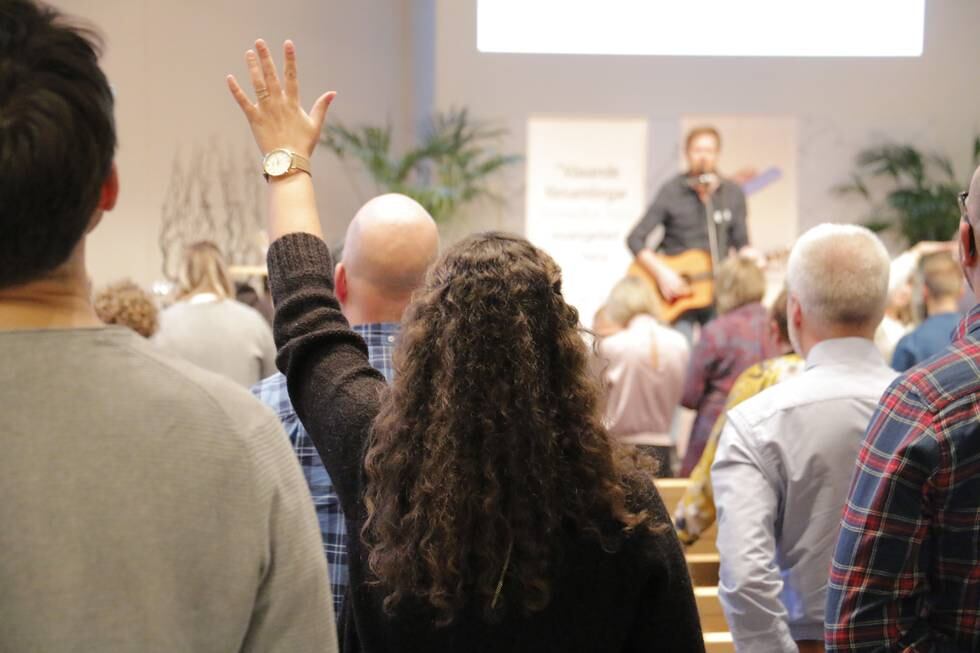 Bön och lovsång. Bild tagen så ryggar syns bakifrån. Evangeliska frikyrkans medarbetardagar i Ryttargårdskyrkan, Linköping, 2018.