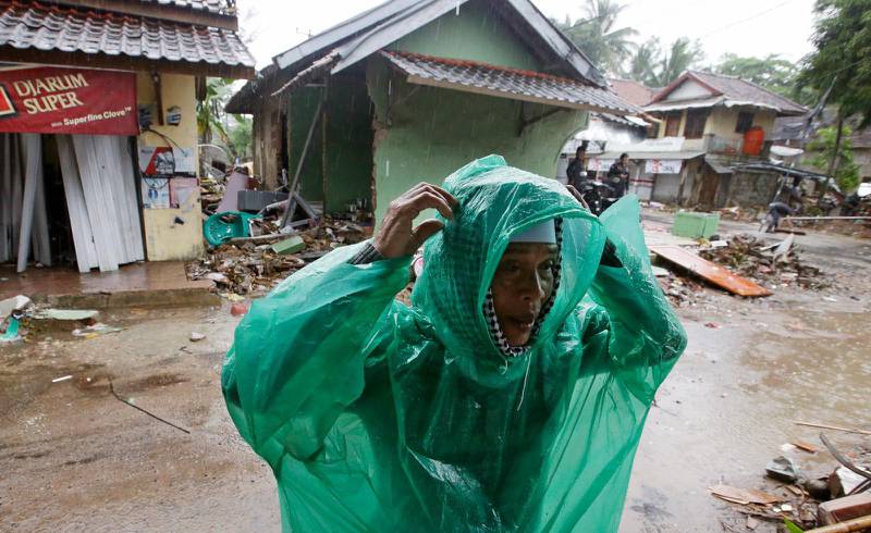 En man sätter på en regnkappa i tsunami-drabbade Caritas.