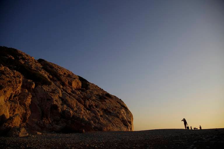 A woman walks by Aphrodite's Rock, 'Petra tou Romiou', the spot where according to ancient Greek mythology the ancient goddess Aphrodite was born, near Paphos, Cyprus, Monday, July 13, 2020. (AP Photo/Petros Karadjias)