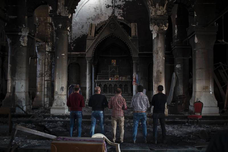 Fyra kristna irakiska män i stilla bön i en kyrka i staden Qaraqosh, som ligger öster om Mosul. Qaraqosh, den största kristna staden på Nineveslätten, erövrades av IS 2014.