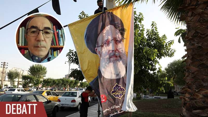Två arbetare hänger upp en banderoll som visar presidentkandidat Ebrahim Raisi.
