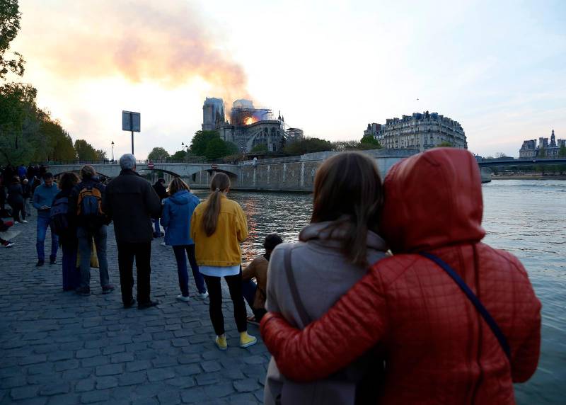 Oroliga Parisbor ser på avstånd när den ikoniska 1100-talskyrkan brinner.