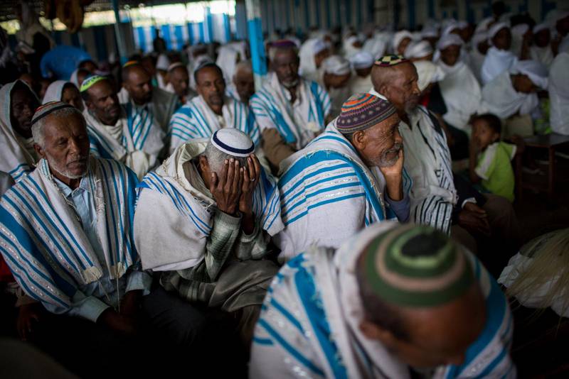 Etiopiska judiska män i kippa och bönesjal samlas i synagogan för morgonbön.