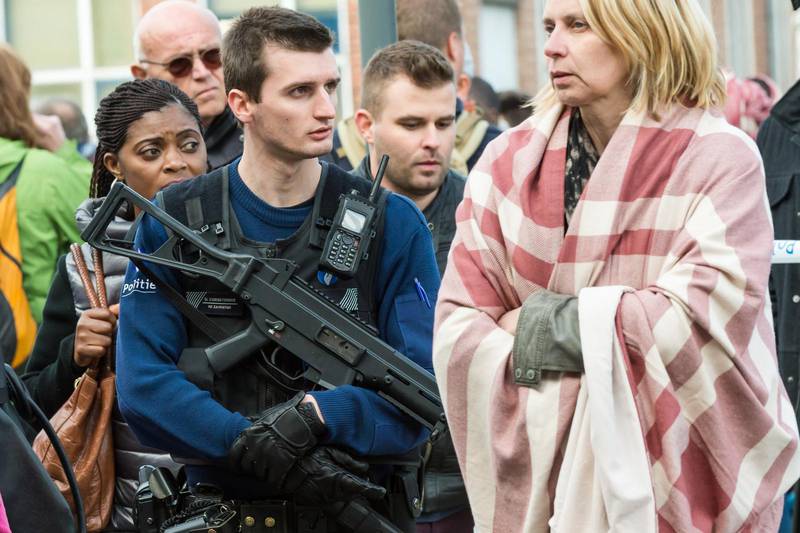 En polis står redo medan människor evakueras från Bryssels flygplats efter terrordådet.