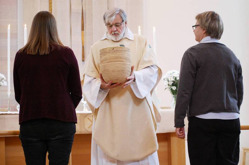 De två kyrkvärdarna och prästen Hans Lindholm ber för de insamlade pengarna.