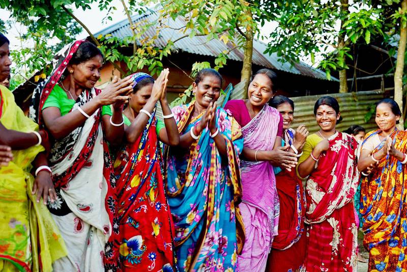 När andra barn gick i skolan fick de här kvinnorna stanna hemma. Därför dansar de av glädje nu när de i vuxen ålder får lära sig läsa genom ett svenskt alfabetiseringsprojekt. De tillhör ett fattigt minoritetsfolk, santalerna, i norra Bangladesh.