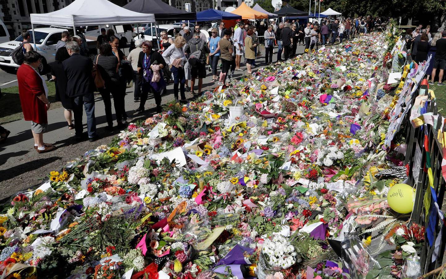 People view messages at a floral tribute at the Botanical Gardens in Christchurch, New Zealand, Tuesday, March 19, 2019. Christchurch was beginning to return to a semblance of normalcy Tuesday. Streets near the hospital that had been closed for four days reopened to traffic as relatives and friends of Friday''s shooting victims continued to stream in from around the world. (AP Photo/Mark Baker)