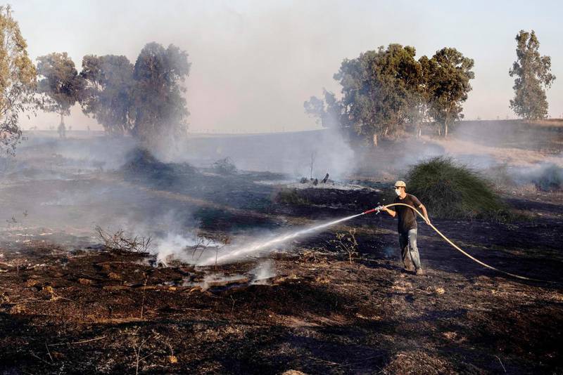 En israelisk man bekämpar bränder som orsakats av raketer och brandbomber.