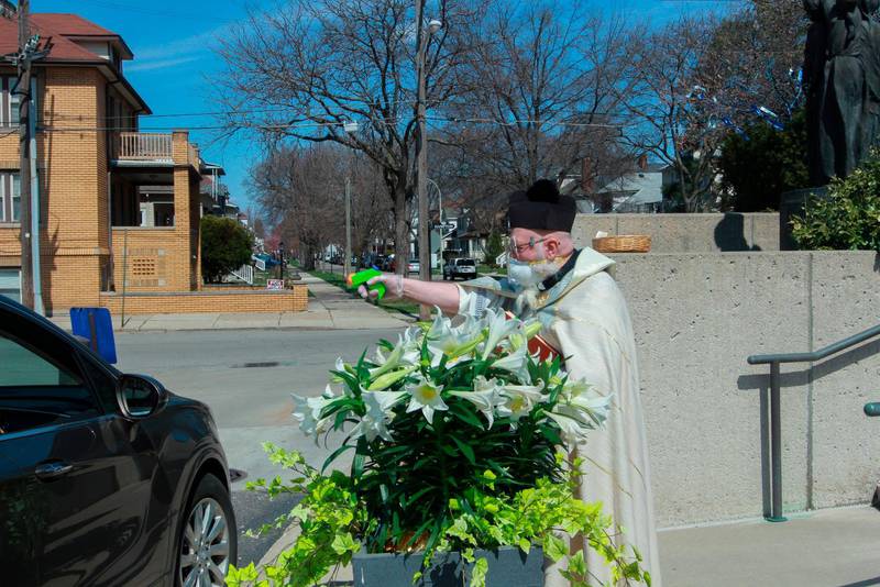 Timothy Pelc välsignar påskkorgar som passerande sträcker fram  utanför kyrkan St. Ambrose i Grosse Pointe Park.