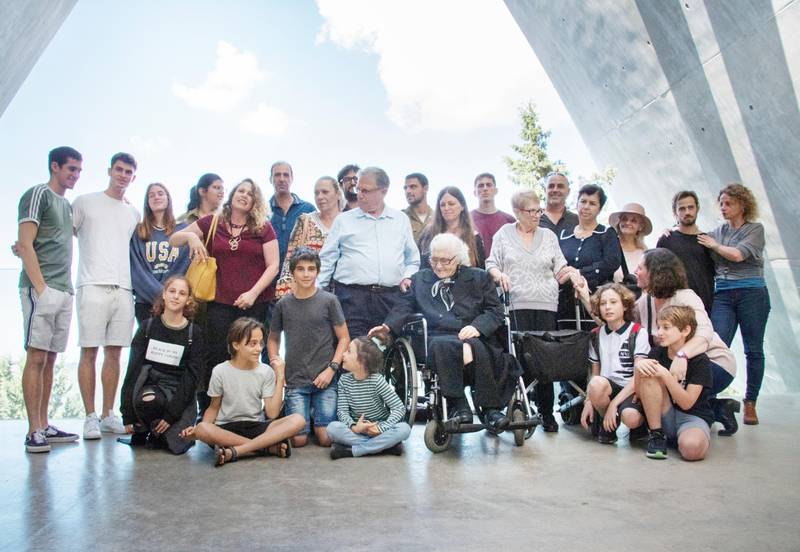 Melpomeni Dina, center right, poses for a group photo during a reunion at the Yad Vashem Holocaust memorial in Jerusalem, Sunday, Nov. 3, 2019. Dina, a 92-year-old Greek woman who rescued a Jewish family during the Holocaust has been reunited with two of the people she saved and dozens of their family members. Once a regular ritual, such reunions are quickly disappearing due to the advanced age of the rescuers and survivors. (AP Photo/Patty Nieberg)  SEB101