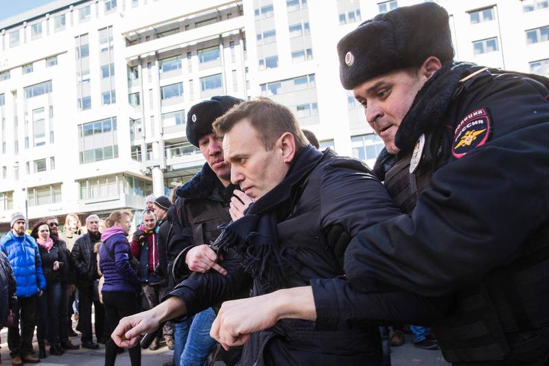 En av de gripna under protesterna i Ryssland är oppositionsledaren Aleksej Navalnyj. Bilden nere till vänster visar en supporter till Navalny som sitter i en polisbil, där någon fäst en röd dekal där det står Navalnyj.