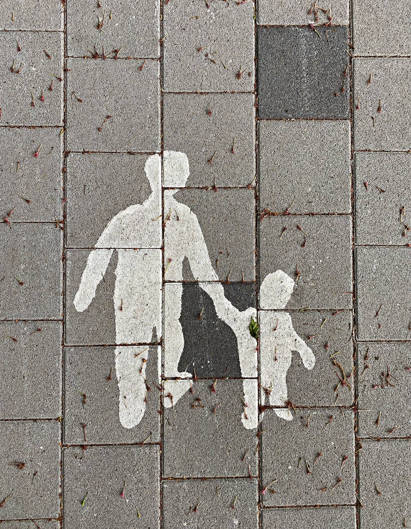 Målning på vägbanan, vuxen håller ett barn i handen.