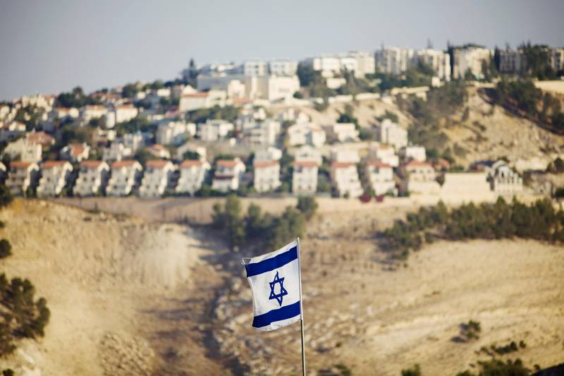 FILE - In this Monday, Sept. 7, 2009 file photo, an Israeli flag is seen in front of the West Bank Jewish settlement of Maaleh Adumim on the outskirts of Jerusalem. The population of Jewish settlers in the occupied West Bank has surged during Prime Minister Benjamin Netanyahu's years in office, growing at more than twice the pace of the overall population, according to official figures obtained in December, 2014. (AP Photo/Bernat Armangue, File)