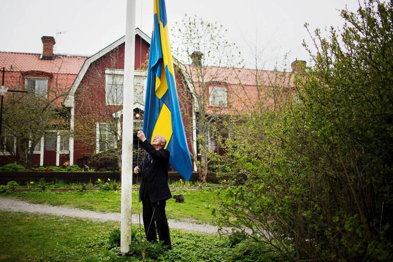 Biskop emeritus Gunnar Weman står på backen och hissar flaggan