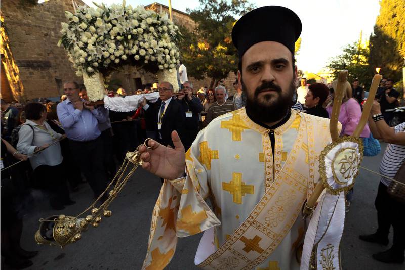 CYPERN. En grekisk-ortodox präst håller i ljusen under långfredagsprocessionen.