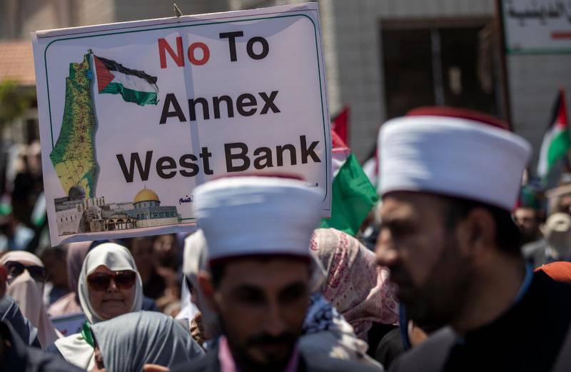 Palestinier i Gaza demonstrerar mot Israels planer. Kartan på plakatet visar en palestinsk stat från Medelhavet till Jordanfloden, efter att Israel utplånats.