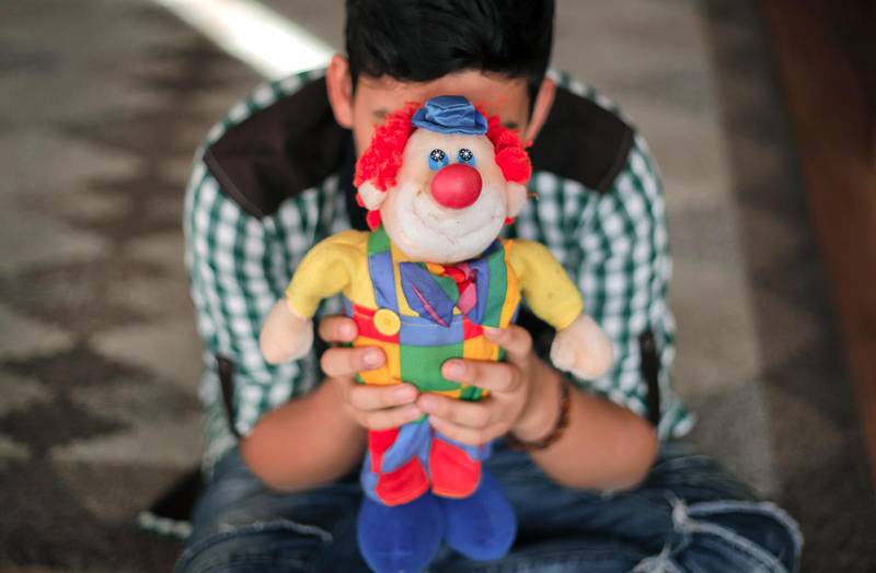 En pojke som bodde i ett hem för övergivna barn döljer sitt ansikte med en clowndocka. Rumänien tömmer sina barnhem och återförenar övergivna barn med sina föräldrar eller placerar dem i fosterhem. Målet är att stänga alla barnhem inom några få år. Är barnhemmen det bästa för barnen, eller för oss själva, skriver Daniel Grahn. Foto: Vadim Ghirda