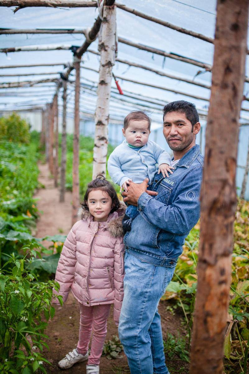 Amir tillsammans med två av barnen i det stora växthuset de byggt själva för att förlänga odlingssäsongen.