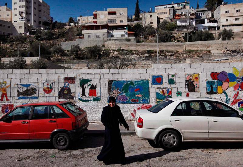 Omtvistat område. En palestinsk kvinna går längs en mur vid en skola i statsdelen Silwan strax utanför Gamla muren i östra Jerusalem. Ir David (Davids stad) ligger delvis i Silwan där en majoritet av invånarna är palestinier.