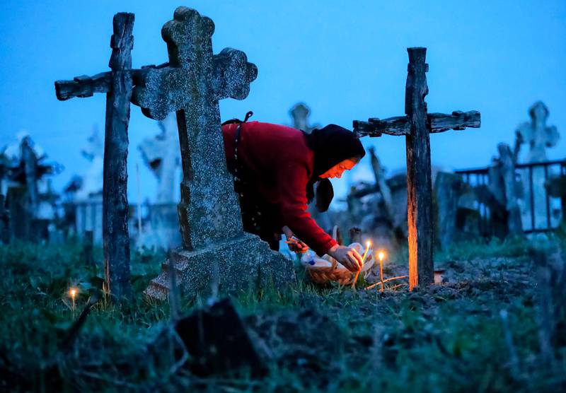 RUMÄNIEN. En kvinna tänder ljus vid sina släktingars grav i Copaciu i södra Rumänien. En gammal tradition i samband med den ortodoxa påsken. 