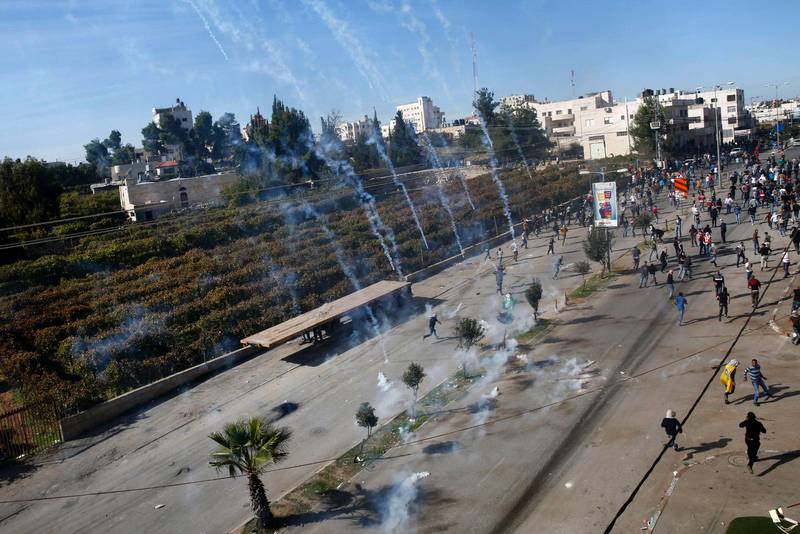 Palestinska demonstranter springer från tårgas som skjutits av israeliska armén i samhället Halhul, nära Hebron på Västbanken.