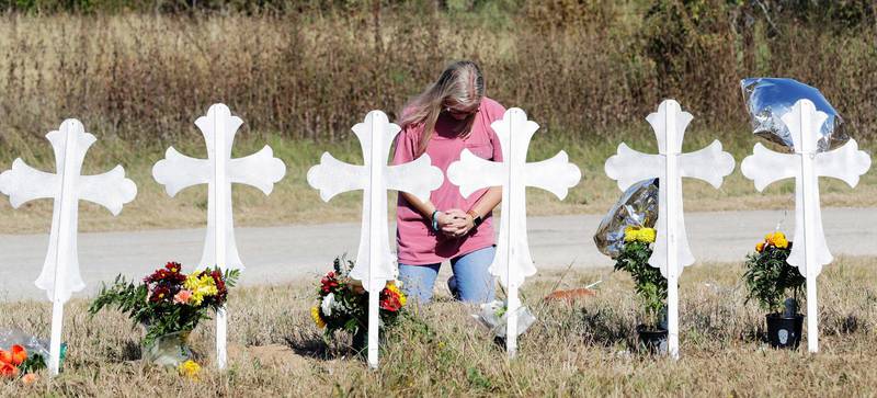 En kvinna knäböjer vid en provisorisk minnesplats för de människor som Devin Kelley sköt ihjäl i First Baptist Church i Sutherland Springs, Texas.