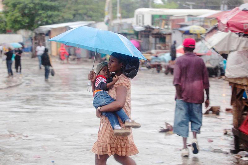 En kvinna vandrar med ett barn i ett blött Port-au-Prince där orkanen Matthew svepte in och orsakade stor förödelse.