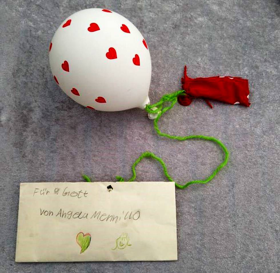 Brev skrivet av tyskt barn, fastknutet i två ballonger, varav den ena spruckit.