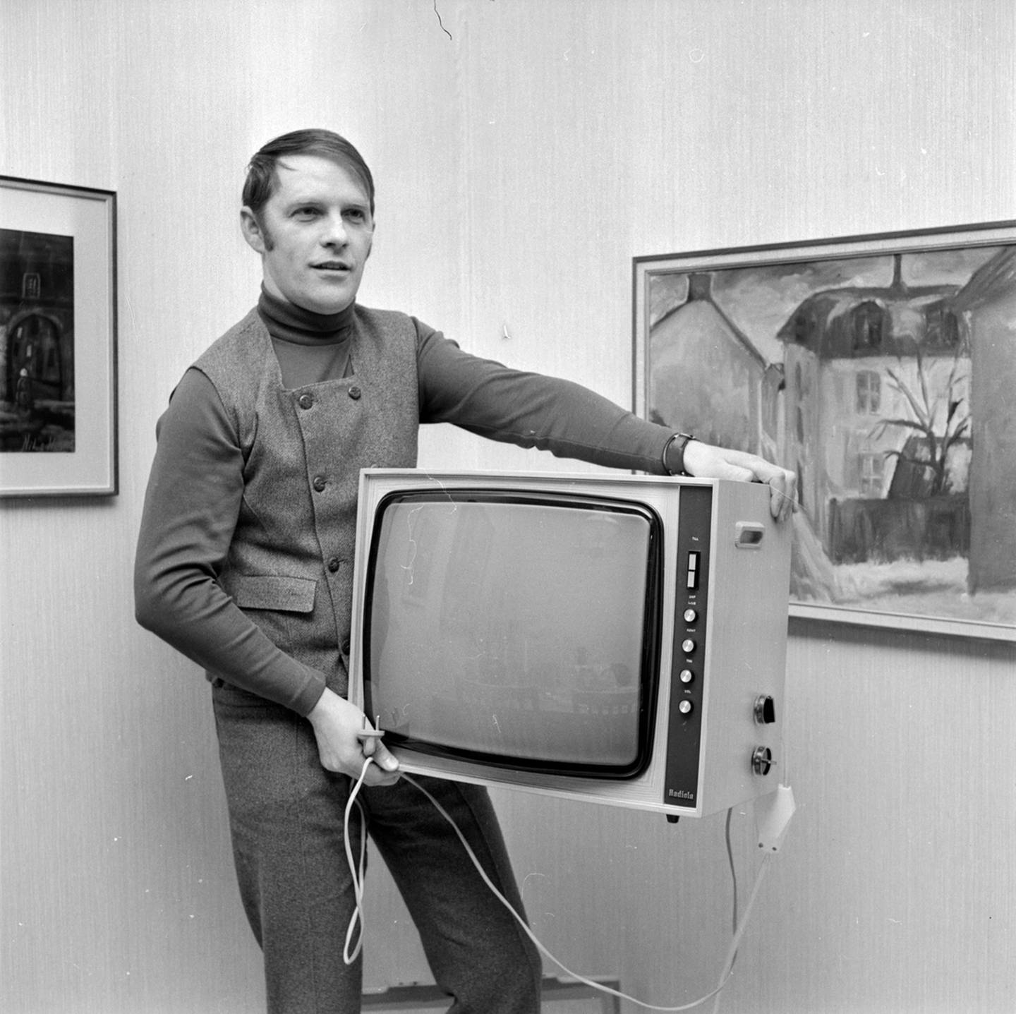 Svartvit bild på Lennart Westlund som bär undan sin tv.