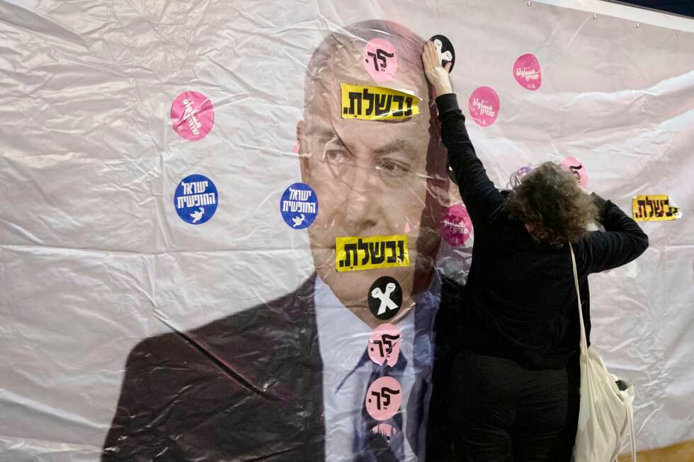 An Israeli protester places a sticker on a banner showing Israeli Prime Minister Benjamin Netanyahu during a demonstration outside the Prime minister's residence in Jerusalem, Saturday, June 5, 2021. Hebrew reads: "You failed" and "Leave". (AP Photo/Sebastian Scheiner)  SEB103