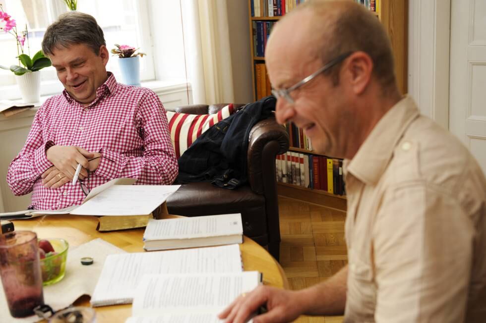 Stefan Swärd och Jonas Gardell sitter vid ett köksbord fullt av böcker.