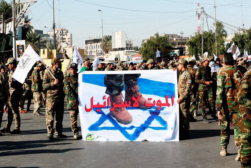 Iranska soldater håller upp en banderoll med ett foto föreställande israeliska flaggan och med texten ”Död åt Israel” vid en protest i Bagdad.