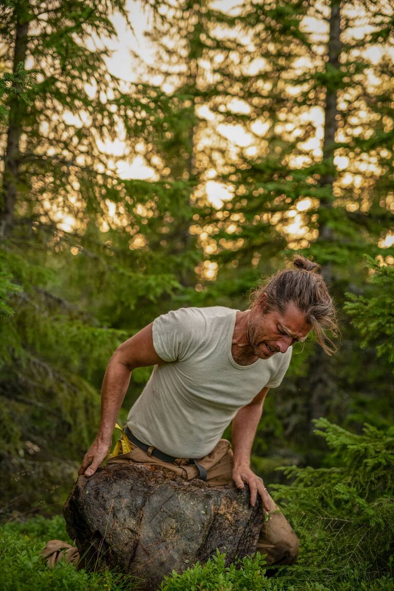 Markus och Frida Torgeby har gett ut boken "En plats på jorden", om att bygga en stuga i den jämtländska skogen, och om livet i stort. Här rullar Markus sten till bygget.
