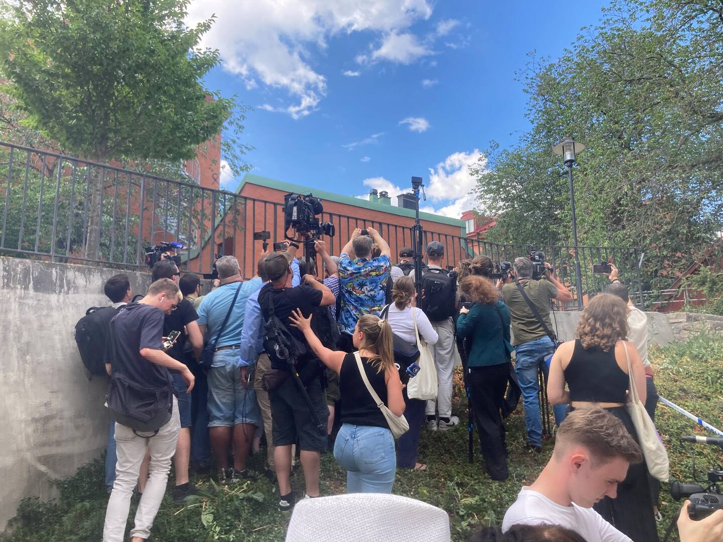 Pressuppbådet trängs för att försöka få en skymt av koranbränningen, som skedde på en uppbyggd grusplan som polisen spärrat av.