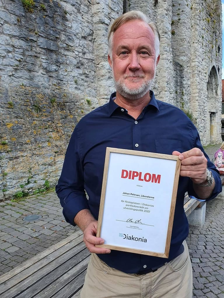 Johan Pehrson (L) visar upp sitt diplom från Diakonia som han tog tack vare att Liberalerna placerade sig på första plats på deras lista, baserat på enkätsvaren från år 2022.