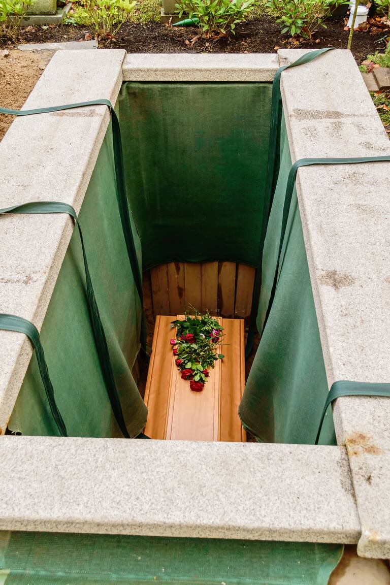 Kista hissas ner i marken på en kyrkogård.