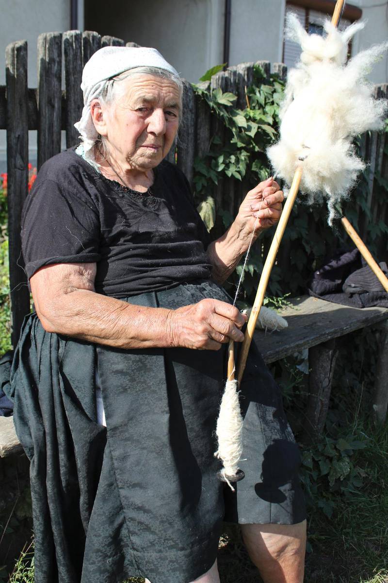 Traditionella kläder är vanligt i norr Rumänien. Den här kvinnan spinner ull utanför sitt hus i Bărsana.